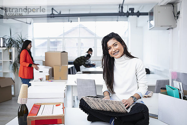 Porträt einer lächelnden  selbstbewussten Geschäftsfrau  die in einem neuen Büro einen Laptop benutzt