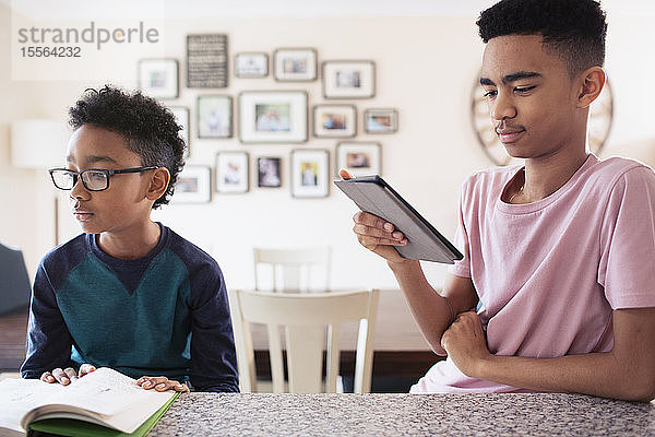 Brüder  die in der Küche lesen und ein digitales Tablet benutzen