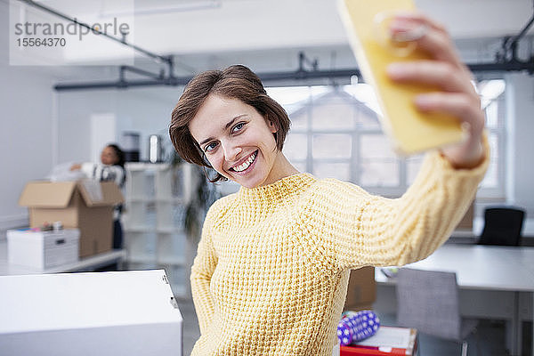 Selbstbewusste Geschäftsfrau macht Selfie im neuen Büro