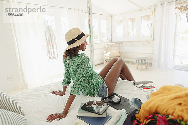 Frau entspannt sich auf dem Bett einer Strandhütte