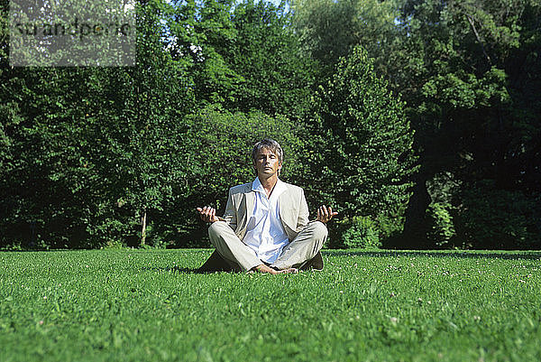 Mittelgroßer  meditierender Mann im Park  Bodenansicht