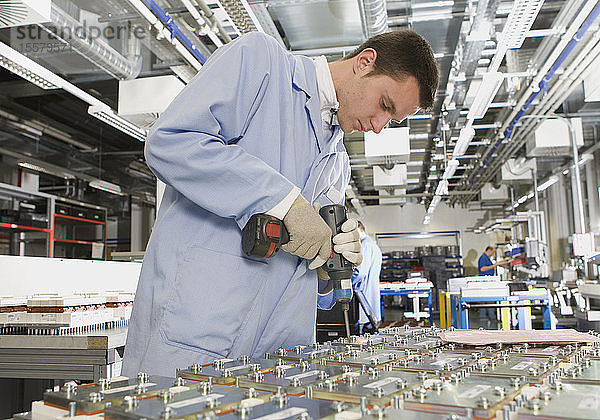 Deutschland  Nürnberg  Junger Mann arbeitet in Fabrik