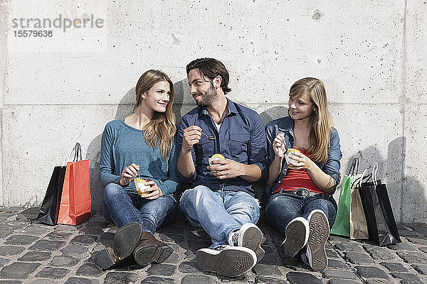 Deutschland  Köln  Junger Mann und Frau mit Eis und Einkaufstaschen  lächelnd
