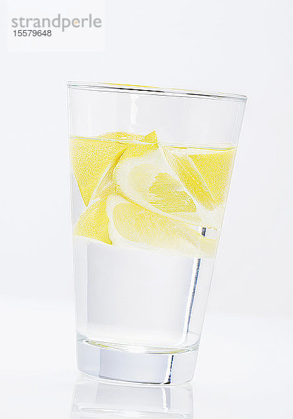 Wasserglas mit Zitronenscheiben auf weißem Hintergrund