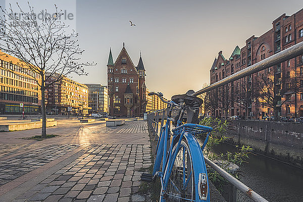 Fahrrad auf Fußweg vor der Speicherstadt bei Sonnenuntergang in Hamburg  Deutschland  geparkt
