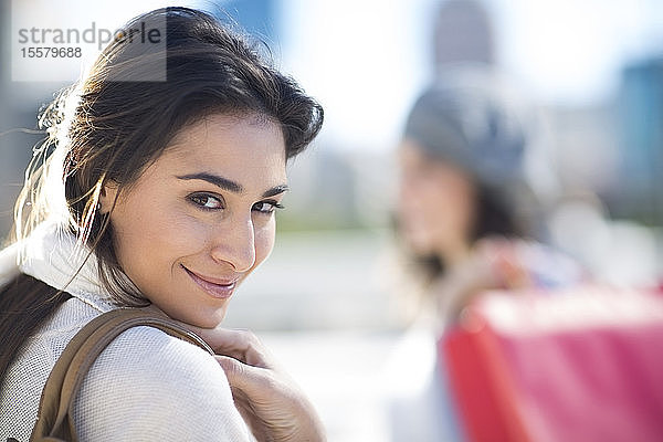Porträt einer lächelnden Frau  die über die Schulter schaut