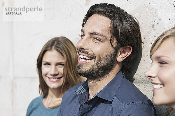Deutschland  Köln  Junger Mann und Frau an Wand gelehnt  lächelnd