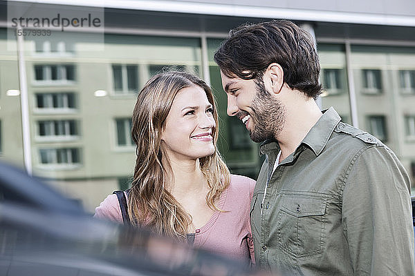 Deutschland  Köln  Junges Paar beim Auto  lächelnd