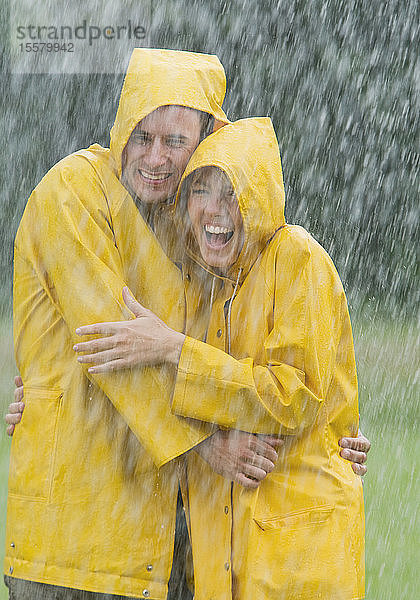 Ehepaar mit Regenmantel im Regen stehend