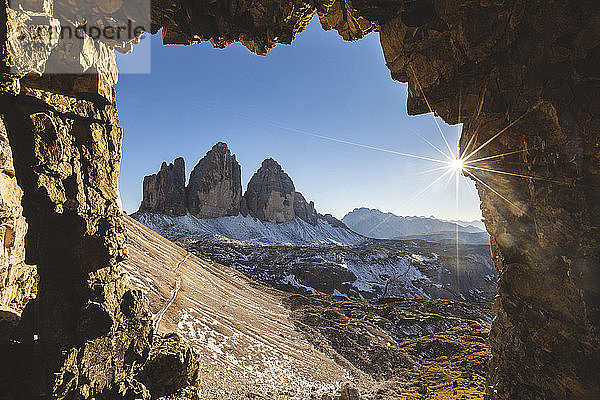 Landschaftliche Ansicht der Tre Cime di Lavaredo durch eine Höhle bei Sonnenschein  Italien