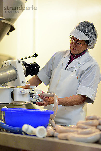 Frau arbeitet bei der Wurstproduktion in einer Metzgerei