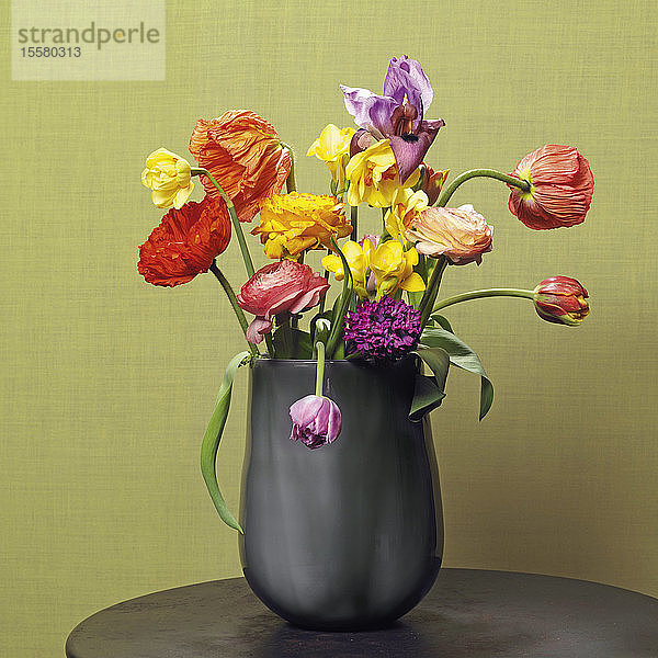Verwelkte Blumen in Vase vor farbigem Hintergrund