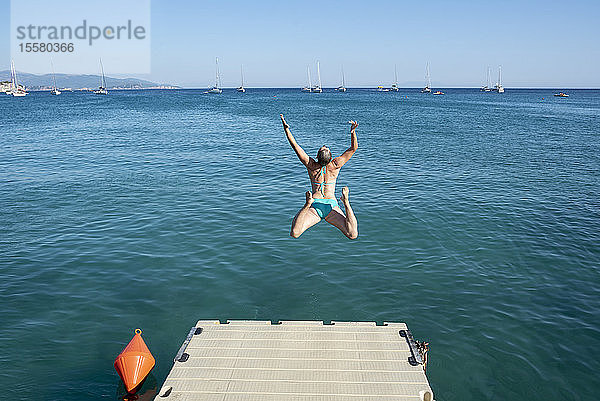 Griechenland  Parga  unbekümmerte Frau springt vom Steg ins Meer