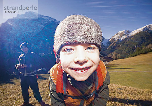 Österreich  Junge lächelnd mit mittelgroßem Mann im Hintergrund