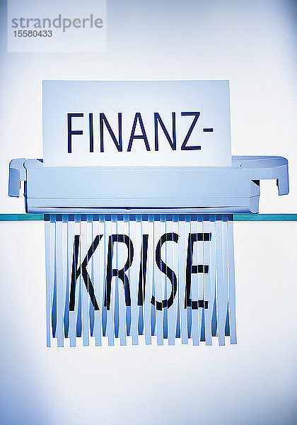 Begriff Finanzkrise beim Schreddern von Papier im Aktenvernichter
