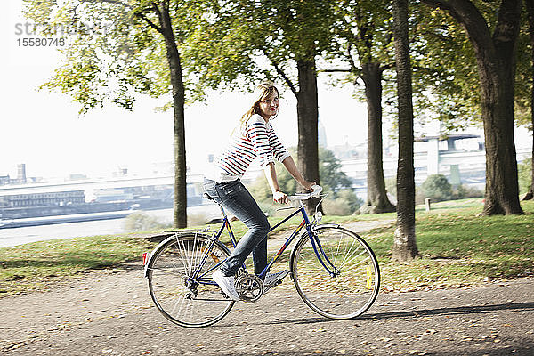 Deutschland  Köln  Junge Frau auf Fahrrad  lächelnd  Portrait