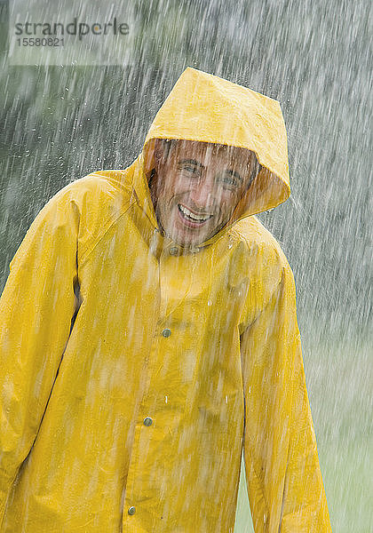 Mann mit Regenmantel im Regen stehend  Porträt