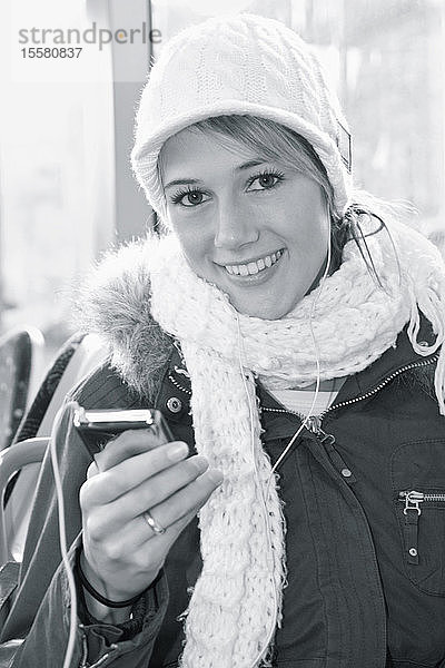 Deutschland  Augsburg  Junge Frau hört iPod  Porträt  lächelnd