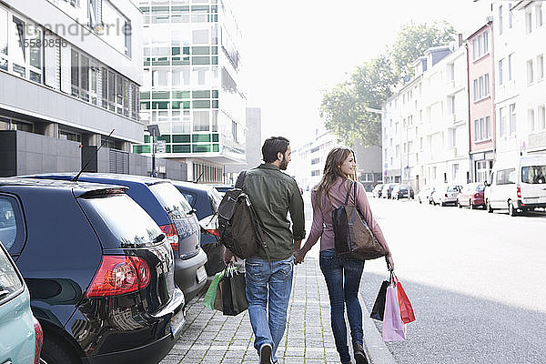 Deutschland  Köln  Junges Paar mit Einkaufstaschen in der Nähe des Parkplatzes  lächelnd