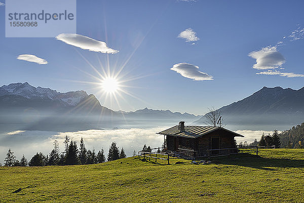Blockhütte am Wank gegen die Zugspitze und Wolkenlandschaft im Sonnenuntergang  Bayern  Deutschland