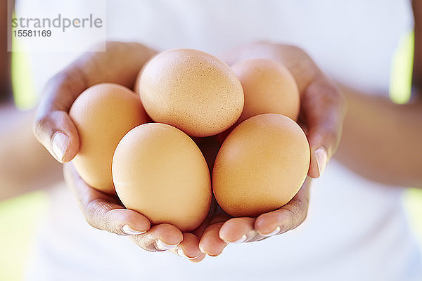 Frauenhände halten braune Eier