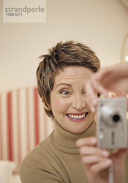 Reife Frau beim Selbstfotografieren mit Digitalkamera