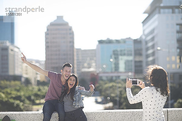 Frau fotografiert glückliches junges Paar mit Smartphone
