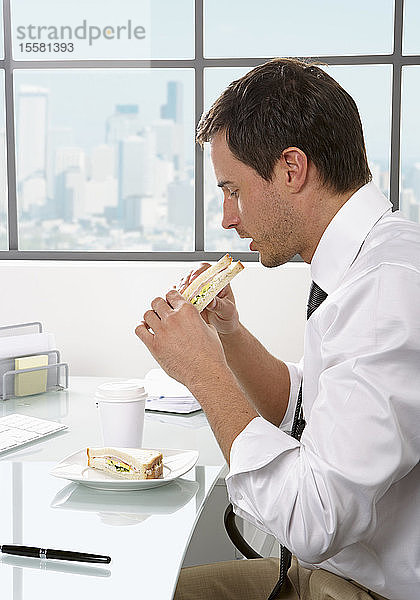 Geschäftsmann isst Sandwich an seinem Schreibtisch