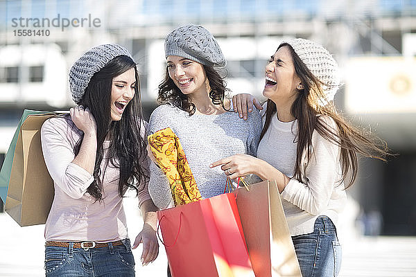 Drei Freundinnen mit Wollmützen und Einkaufstaschen