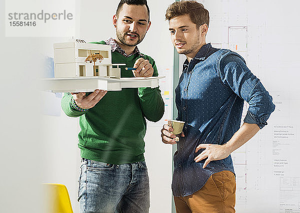 Zwei junge Architekten im Büro diskutieren über Architekturmodell