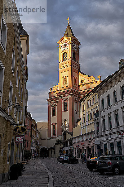Tiefblick auf die Kirche St. Paul vor bewölktem Himmel in Passau bei Sonnenuntergang