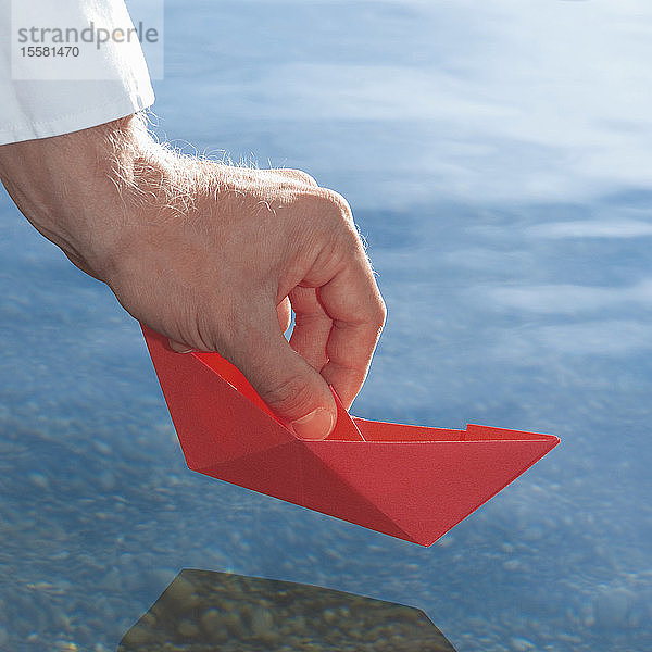 Deutschland  Menschliche Hand hält rotes Origami-Boot