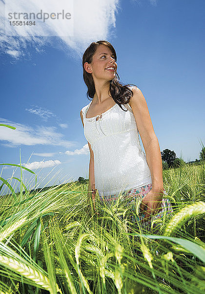 Deutschland  Junge Frau in einem Weizenfeld  lächelnd