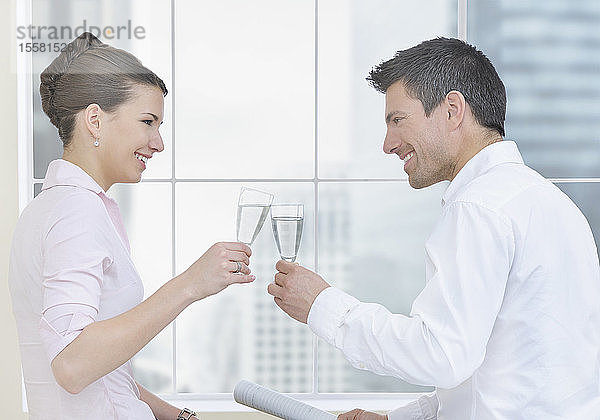 Geschäftsfrau und Mann feiern mit Champagner im Büro und lächeln