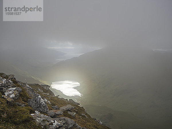 Hochwinkelansicht eines Sees inmitten von Bergen gegen bewölkten Himmel bei nebligem Wetter  Schottland  Großbritannien