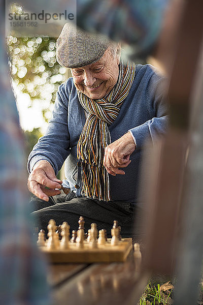 Älterer Mann und Enkel spielen Schach