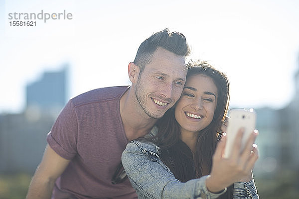 Porträt eines glücklichen jungen Paares  das sich mit einem Smartphone ein Selfie gönnt