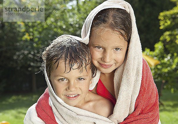 Deutschland  Junge und Mädchen in Badetuch gewickelt  lächelnd  Portrait