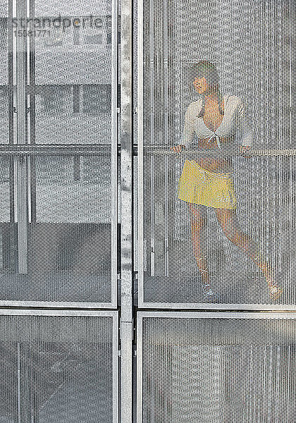 Österreich  Junge Frau hinter Glasfenster stehend