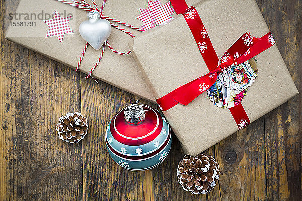 Eingepackte Weihnachtsgeschenke  Weihnachtskugeln und Tannenzapfen auf dunklem Holz
