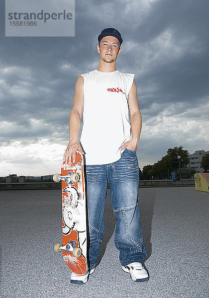 Österreich  Junger Mann mit Skateboard  Porträt