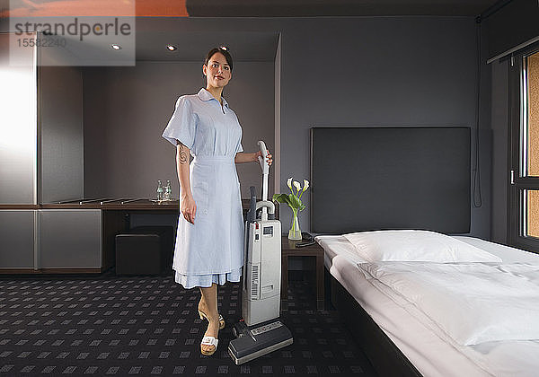 Deutschland  Zimmermädchen mit Staubsauger in einem Hotelzimmer