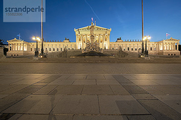 Außenansicht des beleuchteten österreichischen Parlamentsgebäudes in Wien gegen den klaren blauen Himmel bei Nacht