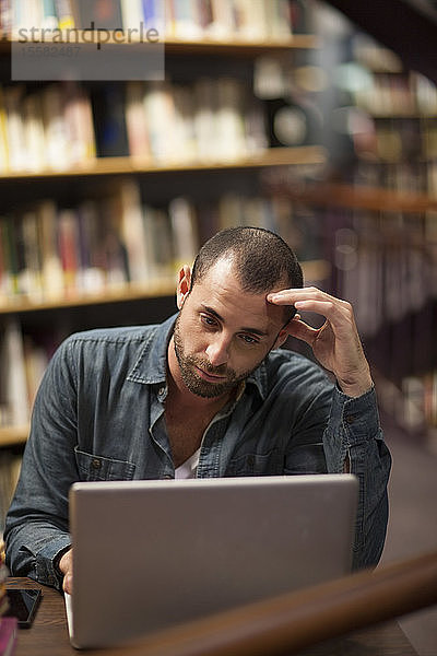 Student benutzt Laptop in einer Bibliothek