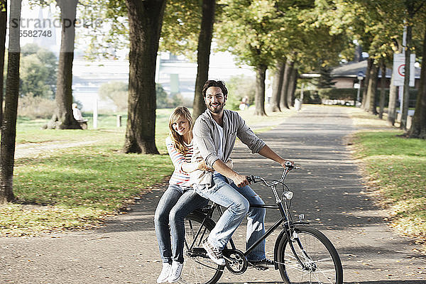 Deutschland  Köln  Junges Paar auf Fahrrad  lächelnd  Porträt