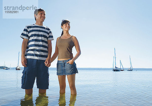 Deutschland  Ammersee  Junges Paar im See stehend  lächelnd