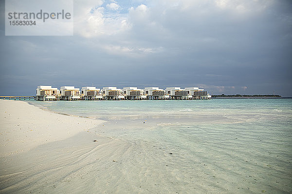 Blick auf Villen über dem Meer vor bewölktem Himmel auf den Malediven