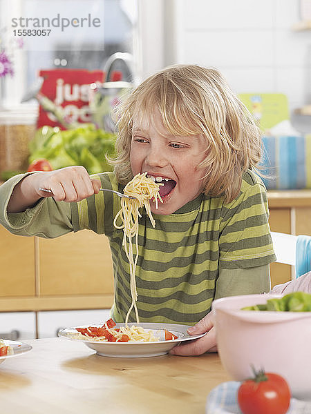 Deutschland  Augsburg  Junge isst zu Hause Spaghetti
