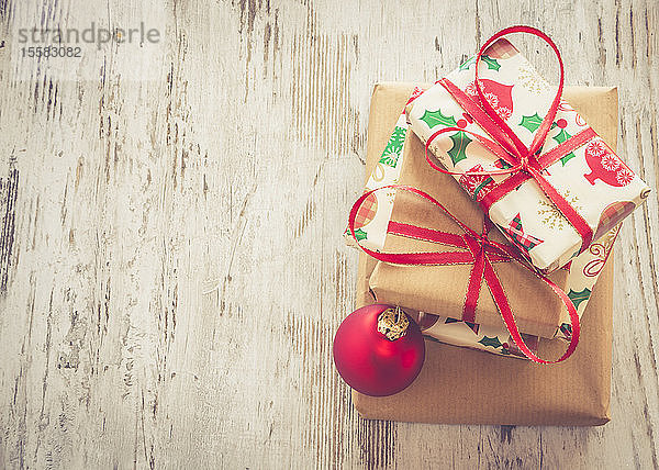 Stapel Weihnachtsgeschenke und rote Weihnachtskugel auf Holz