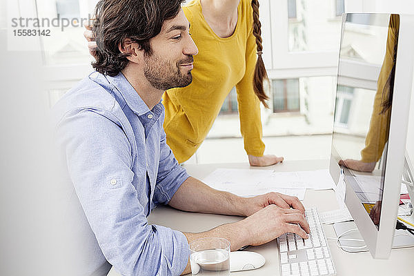 Ehepaar im Heimbüro mit Mann am Computer